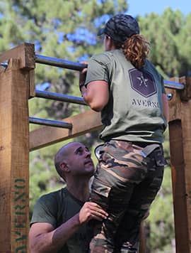 Campamento militar Averno. Recluta de la Promoción Alpha realizando el test de dominadas, mientras un compañero la asiste.